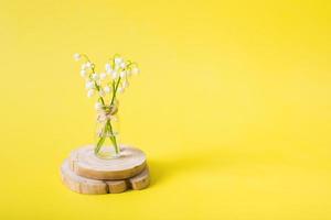 buquê de lírios do vale em uma jarra em miniatura em um fundo amarelo com espaço de cópia. cartão em branco do dia das mães foto