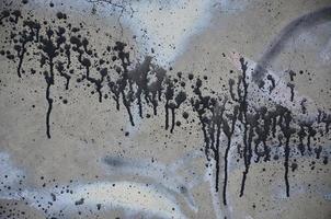 uma fotografia de um close-up de manchas de tinta preta em uma parede de concreto. derramando tinta na parede em ordem aleatória. o conceito de graffiti e cultura de arte de rua foto