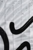 um fragmento de um padrão de graffiti, aplicado a uma parede de azulejos frios, que é coberto por um fino condensado. o conceito de arte de rua em clima impróprio foto