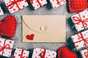 correio de envelope com coração vermelho e caixa de presente sobre fundo cinza de cimento. cartão de dia dos namorados, amor ou conceito de saudação de casamento foto