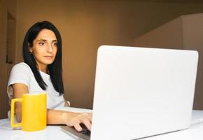 mulher trabalha em casa com caneca de café amarela foto