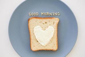 sanduíche no café da manhã em forma de coração com queijo em uma placa azul inscrição bom dia foto