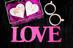 duas xícaras de café, biscoitos em forma de coração inscrição amor close-up foto
