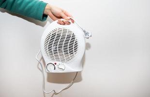 aquecedor isolado em um fundo branco. a garota está segurando um aquecedor de ventilador de plástico. foto