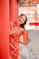 feliz Ano Novo Chinês. bela dama usando vestido cheongsam qipao tradicional segurando o cartão da sorte de bênção no templo budista chinês. texto chinês significa abençoado por uma estrela da sorte. sorriso de emoção foto