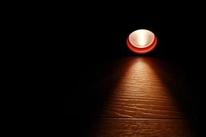lanterna e um feixe de luz na escuridão. uma luz led moderna com projeção brilhante na mesa de madeira escura. superfície com espaço de cópia. falta de energia. colapso do sistema de energia. foto