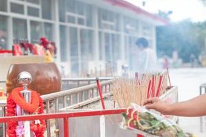 macho colocando incenso na panela para pagar budista no templo da tailândia. foto