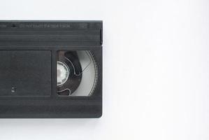 cassete de gravador de videotape vhs preto sobre fundo branco. velha tecnologia obsoleta para gravação em fita e assistir a filmes de mídia. retrô, vintage, história, conceito de nostalgia. postura plana, copie o espaço foto