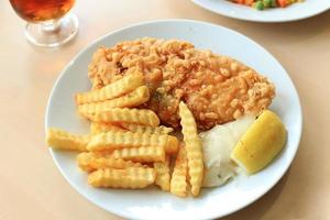 peixe e batatas fritas com molho tártaro, batatas fritas e limão. foto