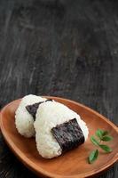 onigiri, triângulo de arroz japonês com alga nori na placa de madeira. foto