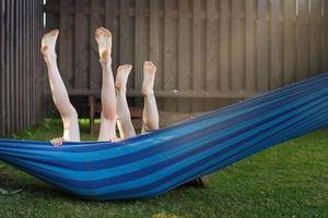 crianças felizes relaxando em uma rede ao ar livre. pés das crianças com os pés descalços. feriados férias foto