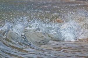 uma onda quebrando na costa de areia foto