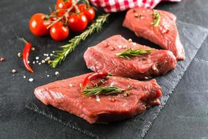 carne crua. bife de carne crua em uma placa preta com ervas e especiarias. fechar-se foto