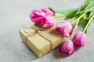 lindas tulipas com caixa de presente. feliz dia das mães, natureza morta romântica em fundo de concreto foto