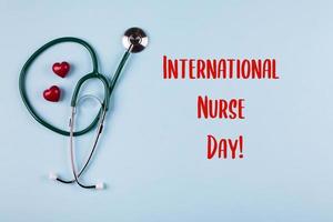 fundo de feriado do dia internacional da enfermeira. estetoscópio médico, dois corações vermelhos e letras de madeira foto