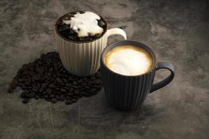latte quente e latte gelado com grãos de café em fundo de concreto. foto