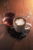 café quente com grãos de café e chá quente em fundo de madeira. foto