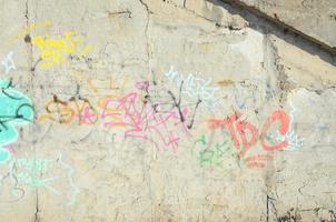 fragmento de close-up de um desenho de grafite aplicado à parede por tinta aerossol. a parede é estragada por uma infinidade de assinaturas coloridas e etiquetas de artistas de rua e hooligans foto