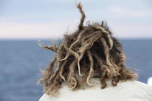 homem rasta cabelo ao vento olhando para o oceano foto