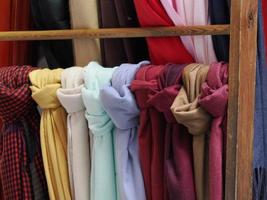 lenços vintage coloridos com diferentes padrões, cores e texturas pendurados em uma prateleira em uma loja ao ar livre foto