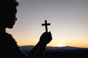 silhueta da mão de uma mulher cristã rezando, mulher segurando um crucifixo rezando, espiritualidade e religião, mulher orando a deus. conceito de cristianismo.