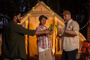 amigos de grupos de turistas acampando e fazendo um churrasco e bebendo cerveja-álcool e quebrando uma garrafa de cerveja com a festa junto com diversão e felicidade no verão foto