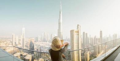 dubai, emirados árabes unidos, 2022 - vista do burj khalifa do céu no centro da cidade, senhora na piscina de borda infinita olhando para o edifício mais alto do mundo. visite dubai sky view hotel nas férias foto
