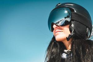 feche o retrato legal da pessoa do sexo feminino do snowboarder com óculos de proteção, olhe para a esquerda com reflexo de montanhas nos óculos de proteção. férias de esqui nas montanhas do cáucaso da geórgia foto