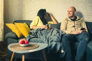 jovem casal multiétnico ri no sofá aconchegante juntos, mulher rindo muito feliz e homem se divertindo, aproveitando o tempo de lazer juntos, relaxando na sala de estar, bons relacionamentos foto