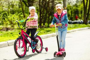 crianças felizes com bicicletas e scooter na natureza foto