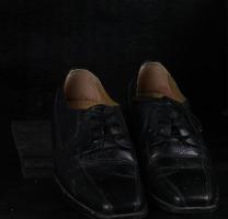 par de sapatos clássicos masculinos pretos sobre fundo preto. sapatos empoeirados foto