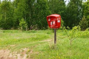 telefone público vermelho. telefone público em pé no campo. telefone da aldeia. Rússia foto