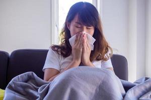 as mulheres asiáticas têm febre alta, dor de garganta, aperto no peito e sofrem de vários sintomas. e muito corrimento nasal, deve cobrir o nariz com lenço de papel porque ela espirra o tempo todo foto