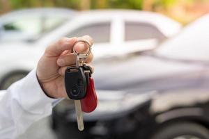 vendendo carro, venda de carro, conceito de negócio, o revendedor dá as chaves do carro ao novo proprietário ou locatário com um contrato de seguro. foto