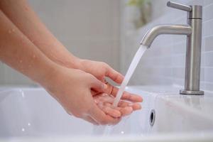 lave as mãos com sabão, evite vírus e bactérias na torneira com água corrente. boa higiene antes de comer ou manusear itens públicos foto
