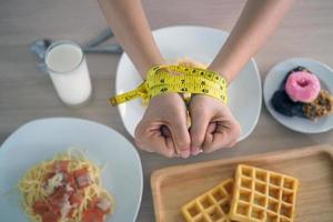 fita métrica em torno dos braços das mulheres. pare de comer gorduras trans, espaguete, rosquinhas, waffles e doces. perder peso para uma boa saúde. conceito de dieta de vista superior foto