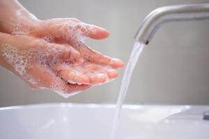 lave as mãos com sabão, evite vírus e bactérias na torneira com água corrente. boa higiene antes de comer ou manusear itens públicos foto