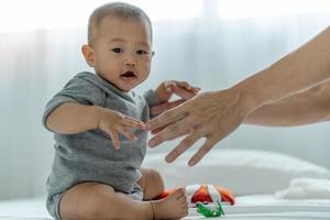 asiático infantil. um bebê asiático confia na mão do pai para se levantar. pai e filho passando tempo juntos foto