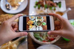 tire uma foto de um smartphone para almoçar ou jantar. mulher tirando foto com telefone. postar ou compartilhar comida popular para a mídia social.