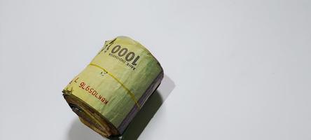 rolo de borracha contendo notas indonésias nominais 1000 rupias isoladas em fundo branco foto