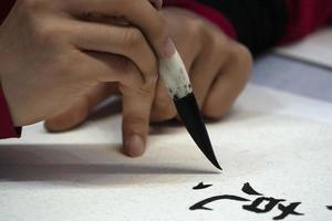 mulher japonesa escrevendo ideogramas com pincel foto