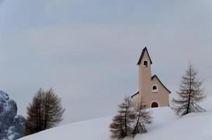 uma pequena igreja de montanha no inverno de fundo de neve das dolomitas foto