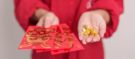 mulher segurando o envelope vermelho chinês com barras de ouro, presente de dinheiro para o feliz feriado do ano novo lunar. frase chinesa significa felicidade, saudável, sortudo e rico foto