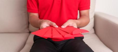 homem segurando envelope vermelho chinês, presente de dinheiro para feliz feriado do ano novo lunar foto