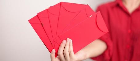 mulher segurando envelope vermelho chinês, presente de dinheiro para feliz feriado do ano novo lunar foto