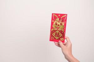 mulher segurando o envelope vermelho chinês com coelho dourado e palavra de bênção, presente de dinheiro para o feliz feriado do ano novo lunar. frase chinesa significa felicidade, saudável, sortudo e rico foto