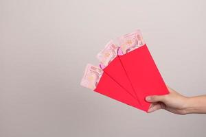mulher segurando envelope vermelho chinês com presente de dinheiro baht tailandês para feliz feriado do ano novo lunar foto