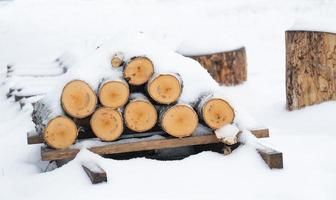 uma pilha de toras para lenha está sob a neve. aquecimento ecológico alternativo no inverno foto