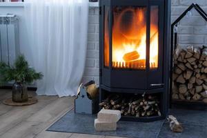 briquetes de combustível feitos de serragem prensada para acender o forno - alternativa econômica de combustível ecológico para a lareira da casa. a lenha está queimando no forno no interior foto