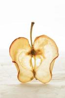 uma fatia de maçã seca está de pé verticalmente no fundo branco. foto